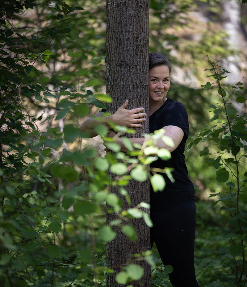Emma William-Olsson kramar ett träd i de sörmländska skogarna.